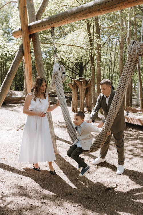 A couple and their son on a swing in the woods