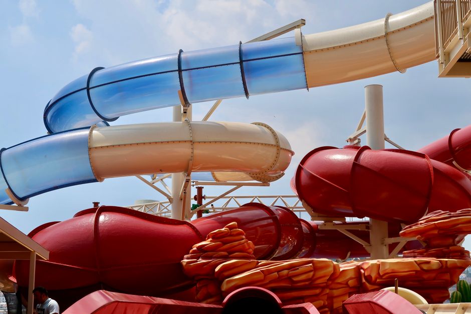 Vibrant water slides in an outdoor amusement park under a clear blue sky.