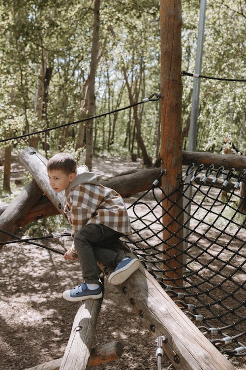 A boy is climbing on a rope net in the woods