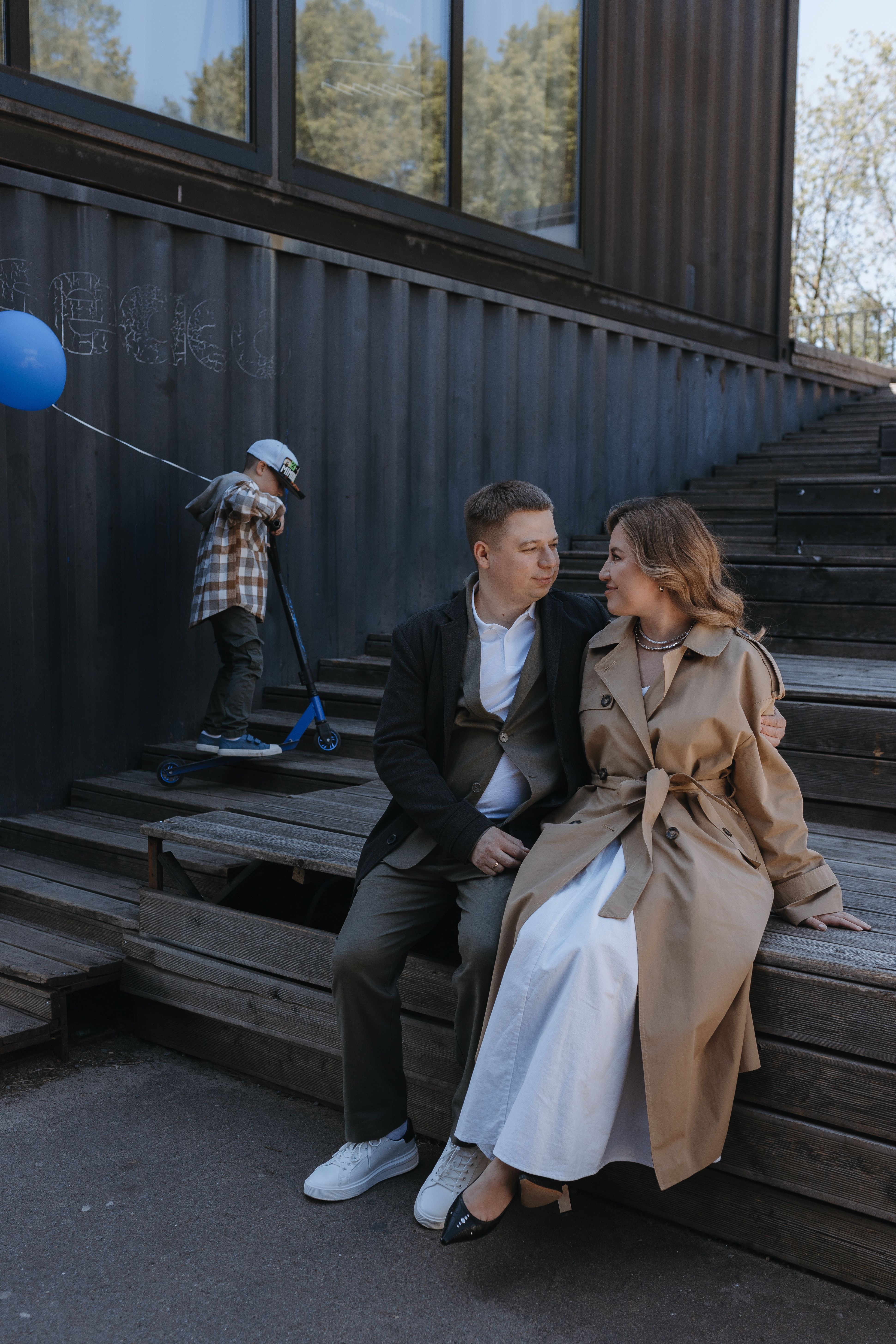 A couple sitting on steps with a boy in a blue balloon · Free Stock Photo