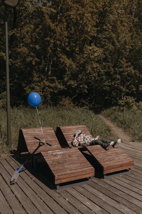 A person laying on a bench with a blue balloon