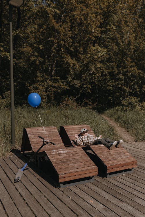 A person laying on a bench with a blue balloon