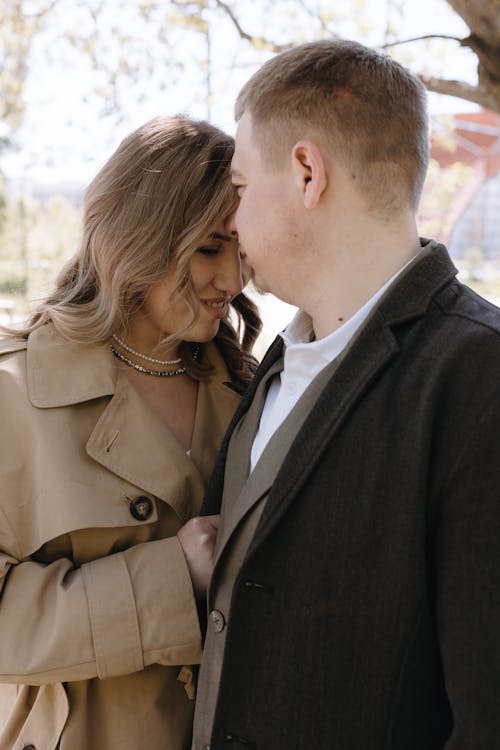 A couple in a trench coat hugging under a tree