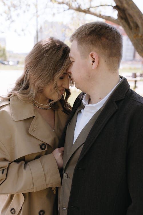 A couple is standing under a tree and hugging