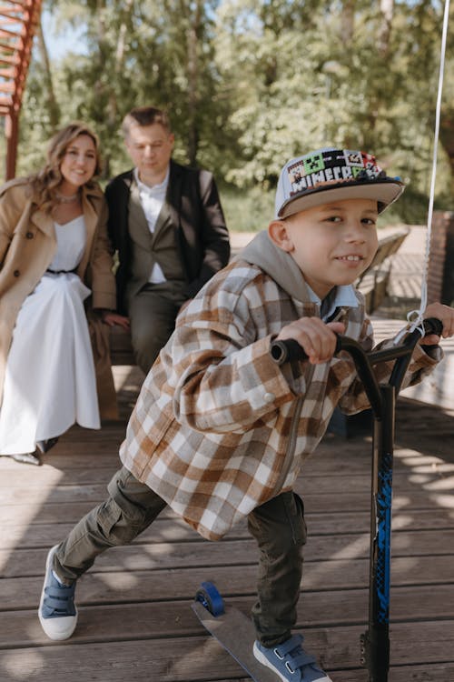 A young boy riding a scooter with his family