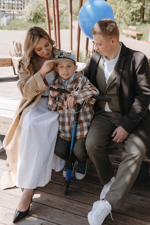 A family is sitting on a bench with a boy in a wheelchair
