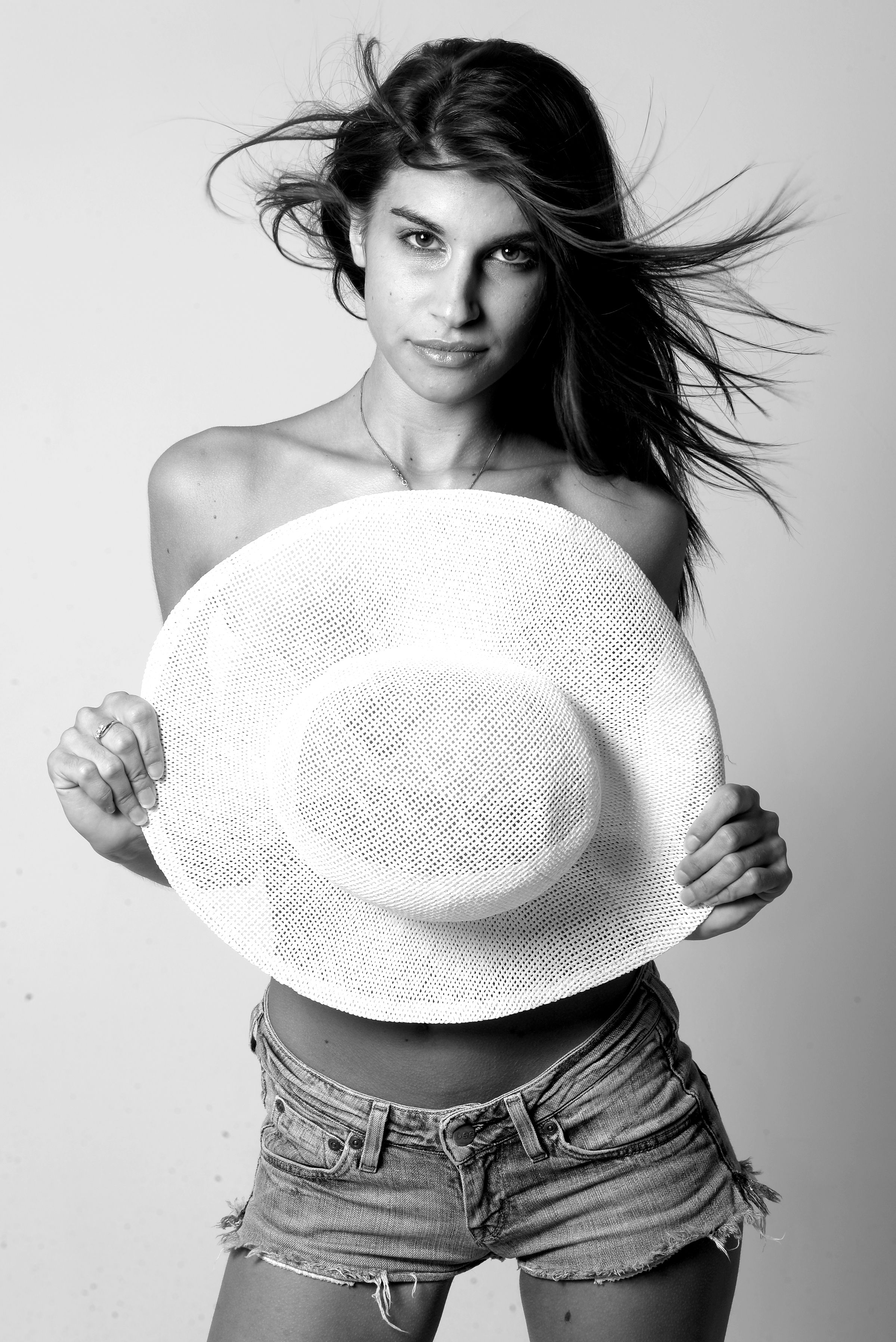 Black and white fashion portrait of a woman holding a hat, showcasing elegance and style.