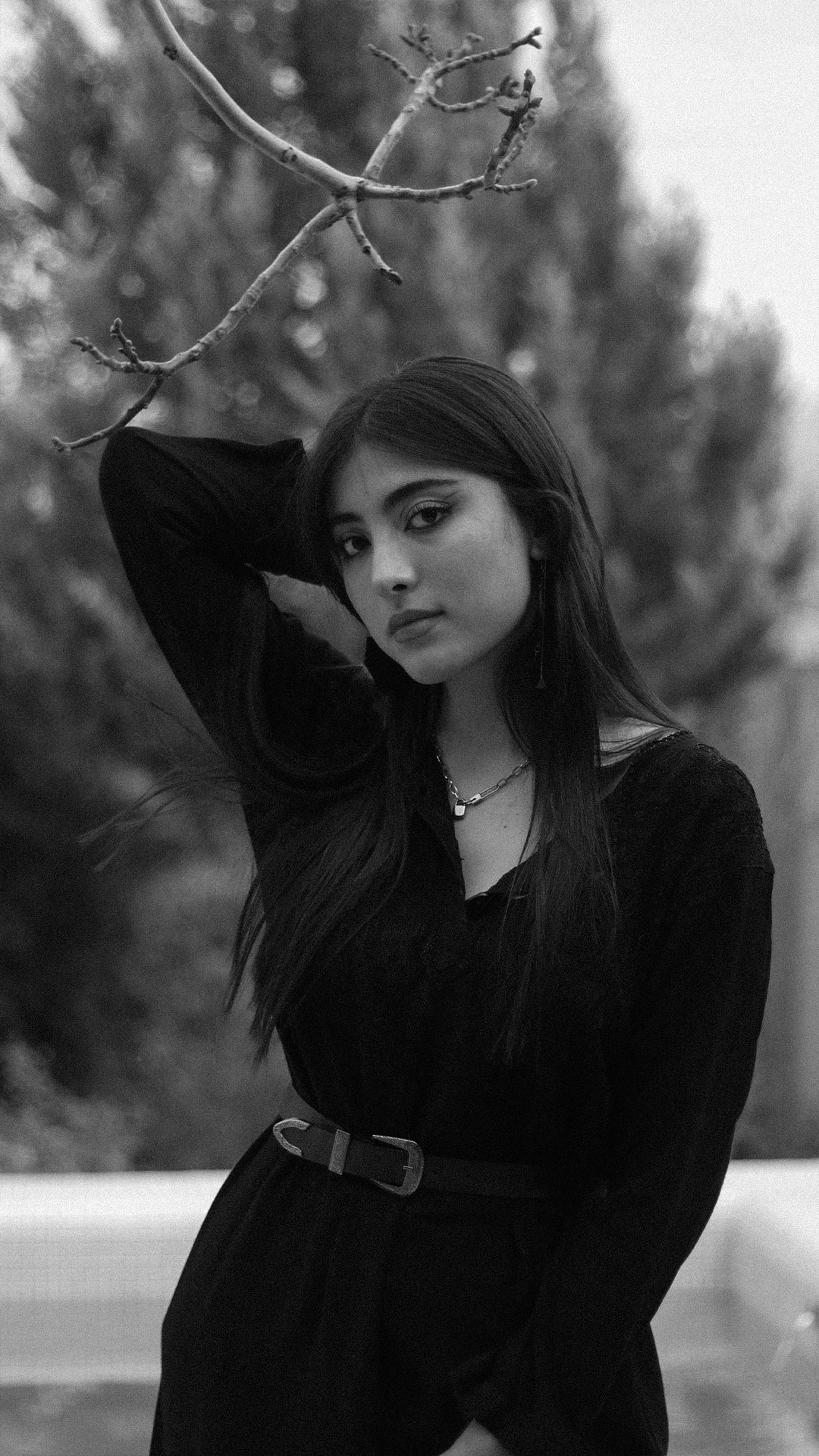 Black and white portrait of a woman posing gracefully outdoors in a natural setting.