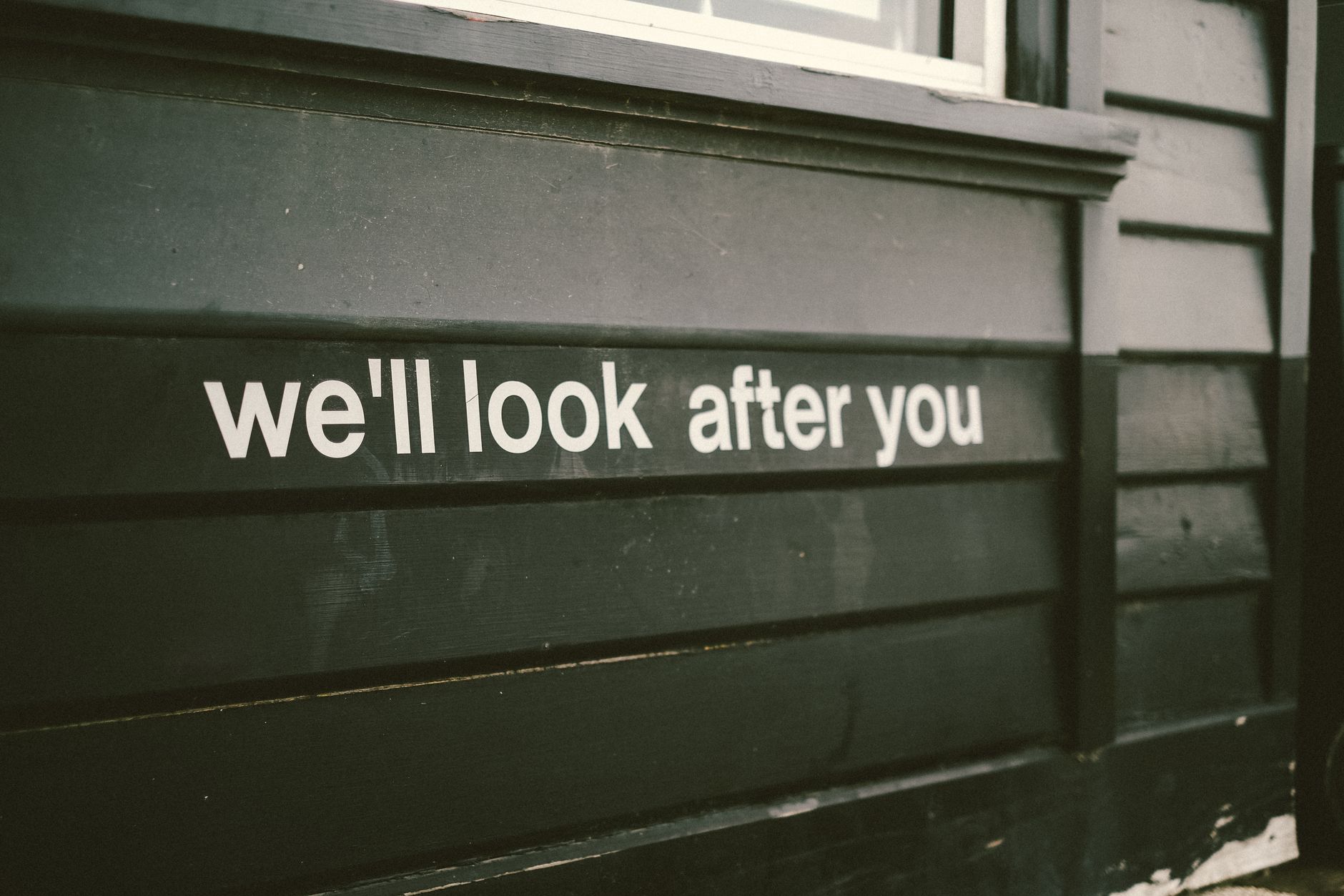Close-up of a wooden facade with the positive message 'We'll look after you.'