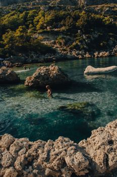 Serene view of Anthony Quinn Bay in Rhodes with swimmers enjoying the clear blue waters.
