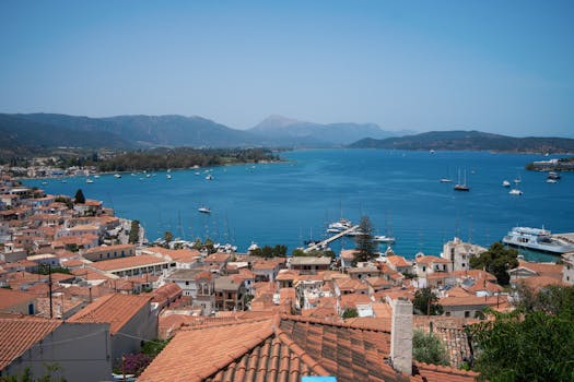 Stunning view of a Greek coastal town with red rooftops and a vivid blue bay filled with boats.