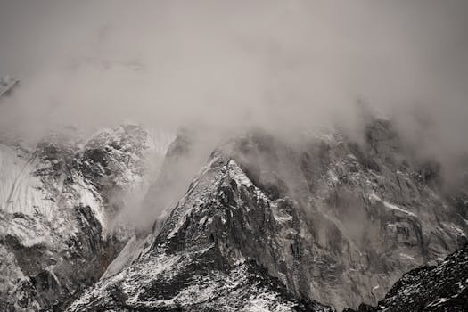 Clouds engulf snow-laden Nepalese peaks, creating a moody winter scene.
