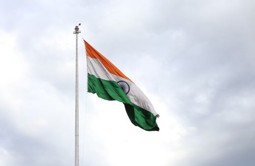 Free Indian flag waving on a flagpole against a cloudy sky, representing patriotism and national pride. Stock Photo