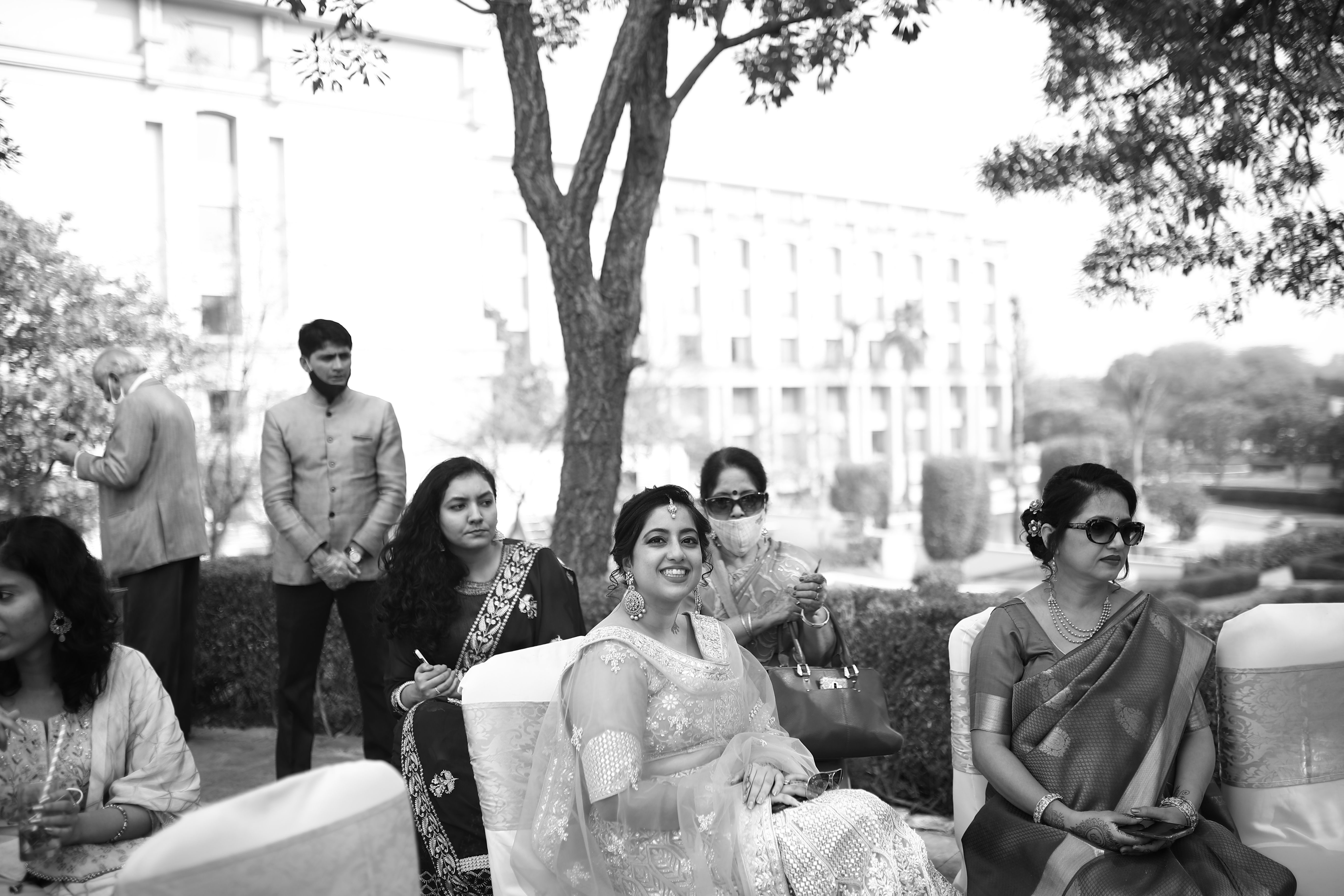 Monochrome image of a joyful outdoor gathering with smiling guests in formal attire.