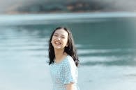 一位开朗的年轻女子穿着格子连衣裙，在宁静的湖边欢笑