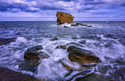 A rock formation in the ocean with waves crashing