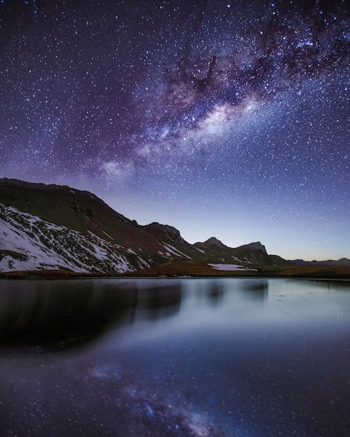 夜空の下で雪と山の近くの湖