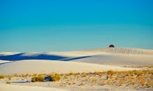 晴朗的蓝天下，宁静的沙漠中，沙丘上搭着帐篷