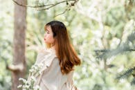 在宁静的户外环境中，一位头发被阳光照射的女人的后视镜，周围环绕着大自然