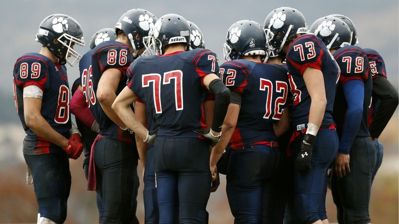 Football-Spieler in dunkelblauen Trikots mit roten Rückennummern stehen im Kreis zusammen