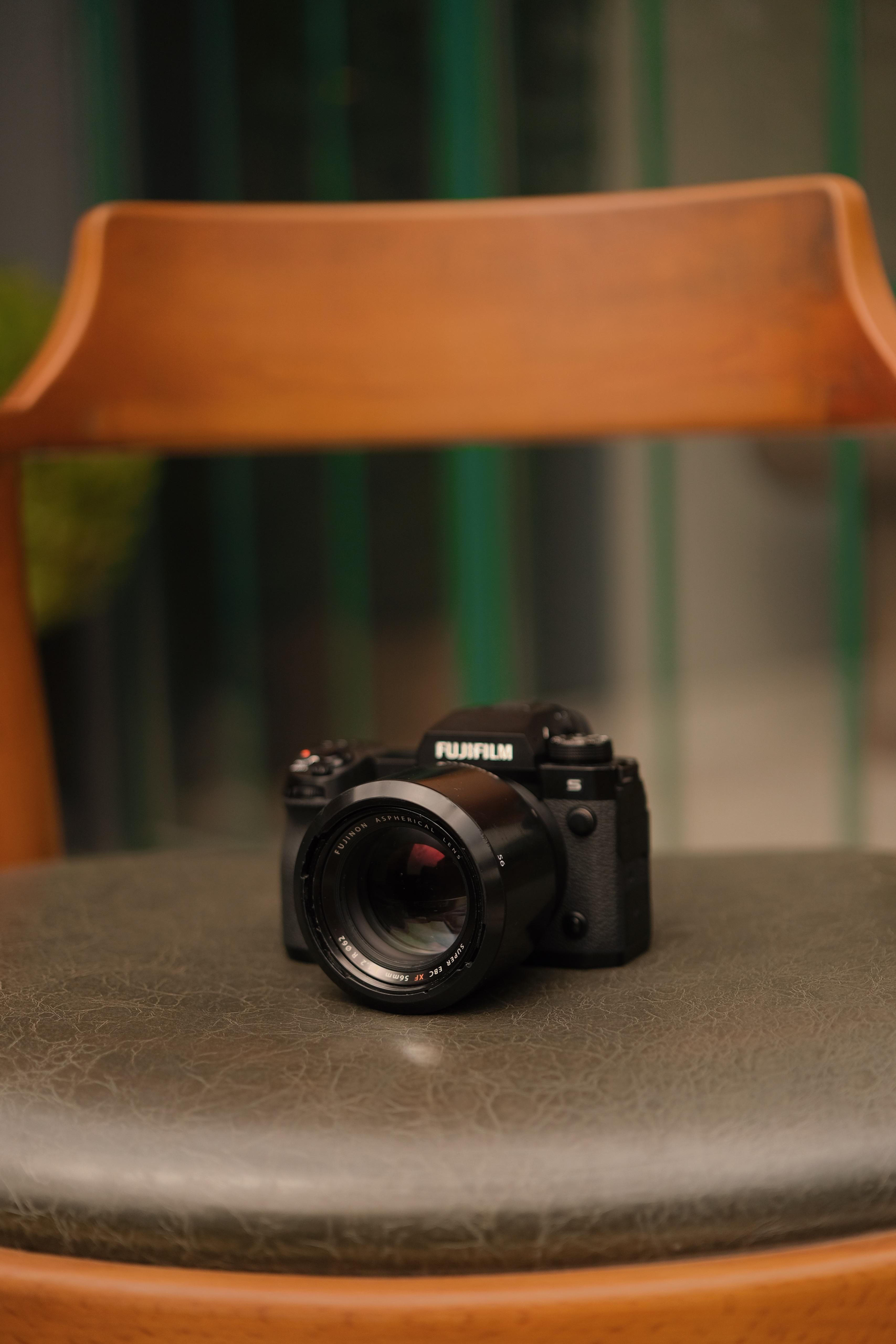 Câmara Fujifilm colocada numa cadeira de madeira estilosa no interior, mostrando um design minimalista.