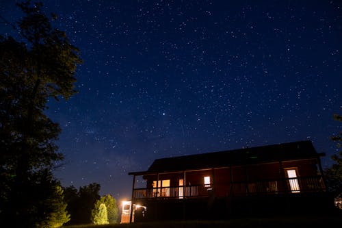 별이 빛나는 밤하늘 아래 조명이 달린 집의 사진