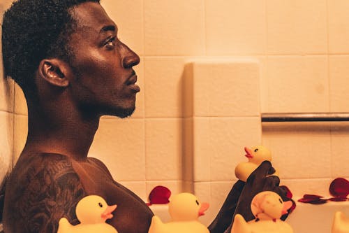 Free Man Sitting in Bathtub with Rubber Ducks Stock Photo