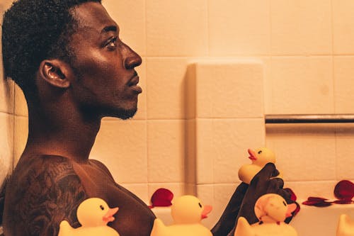 Man Sitting in Bathtub with Rubber Ducks