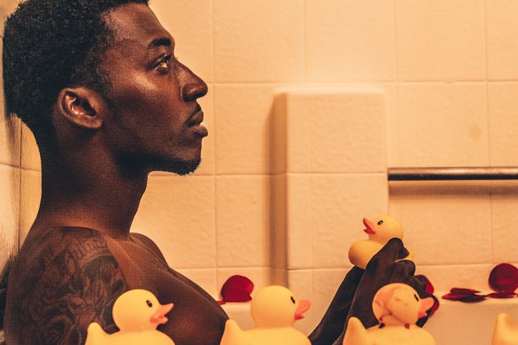 Man Sitting In Bathtub With Rubber Ducks