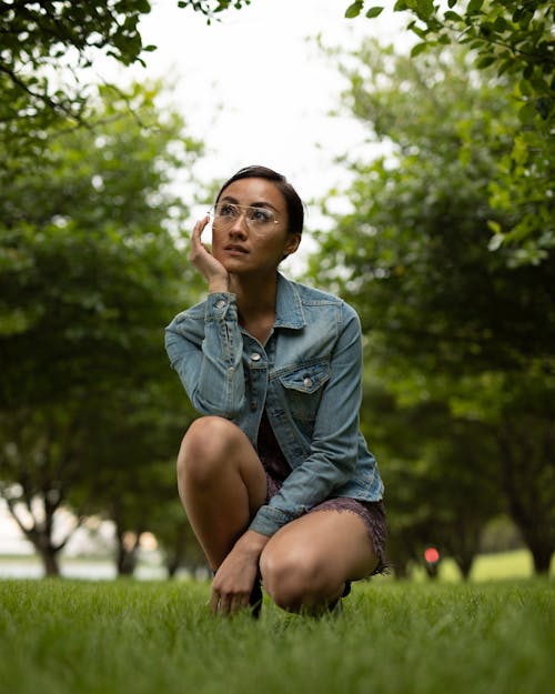 Free Photo of Woman Squat Posing in Park While Looking Up Stock Photo