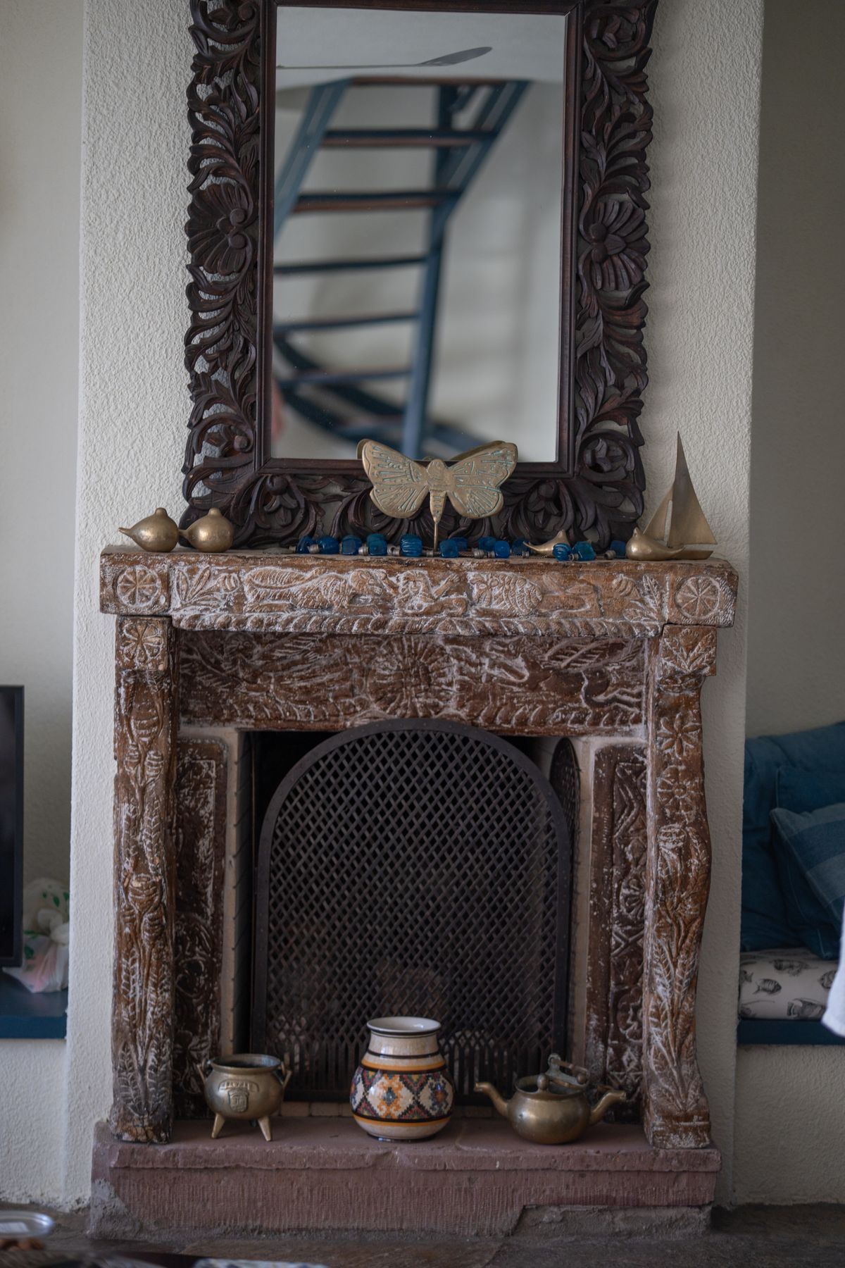 A vintage carved fireplace with a decorative mirror, adorned with various elegant ornaments, enhancing interior design. Stock Photo.