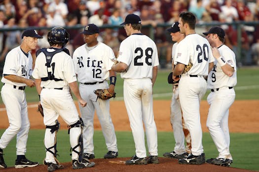 Players and coach discussing strategy during a baseball game on the infield.