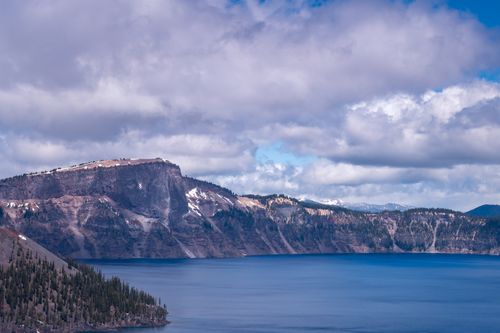 Free Breathtaking view of Crater Lake with snow-capped mountains under a cloudy sky. Stock Photo