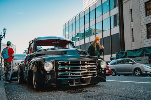 一辆经典的黑色汽车停在城市街道上，行人从旁走过