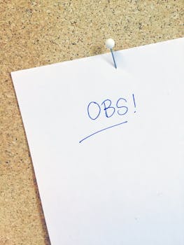 Close-up of a paper with 'OBS!' written on it, pinned to a cork board.