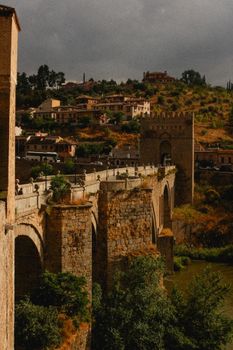 Dramatic view of the historic Alcántara Bridge in Spain surrounded by rustic landscape.