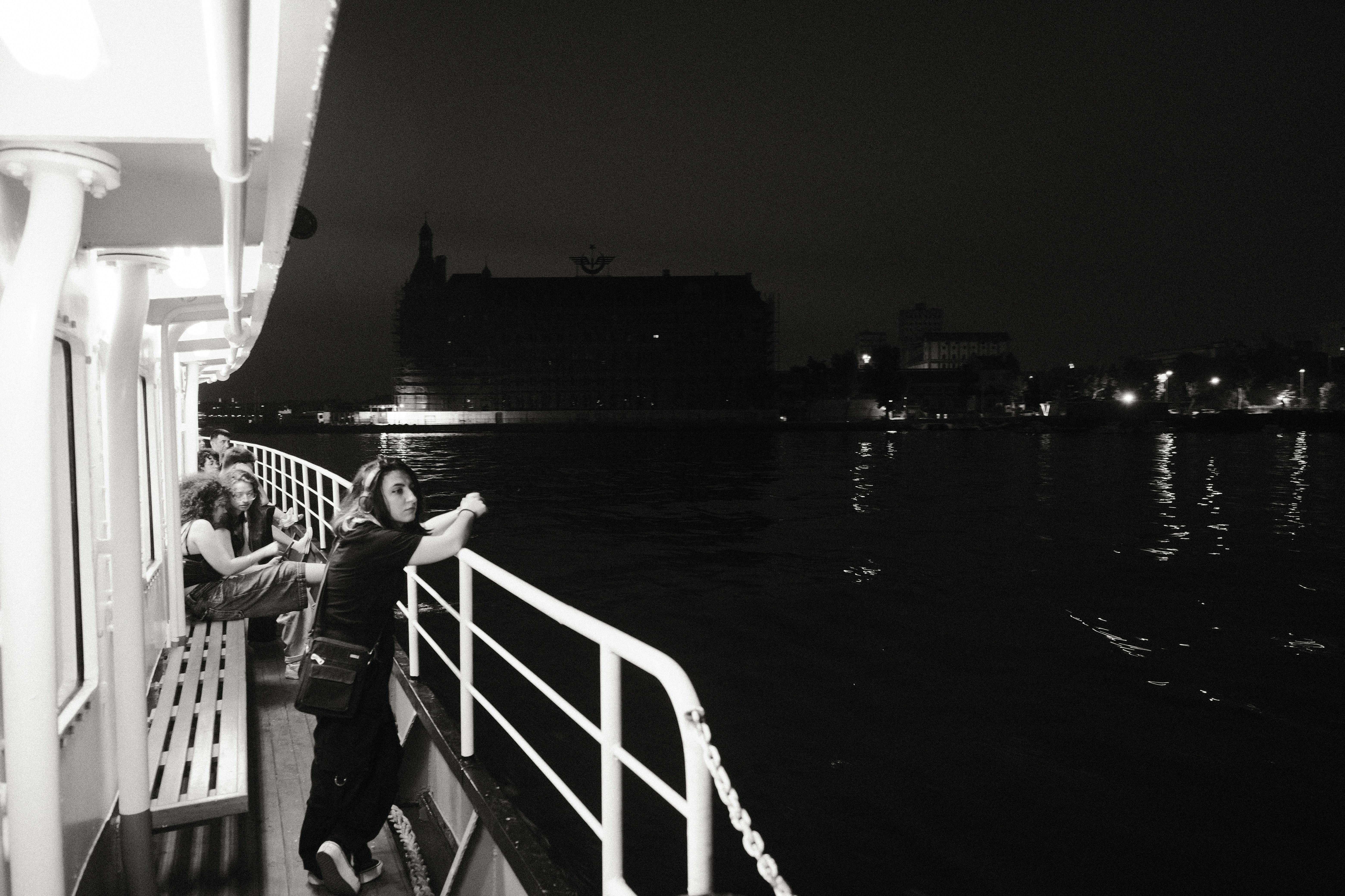 Two people are on the deck of a boat at night