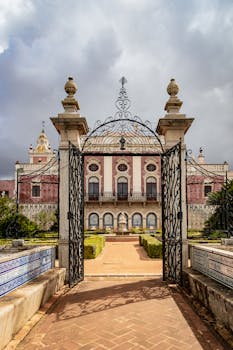 Explore the grand entrance of Estoi Palace in Portugal with intricate iron gates and lush gardens.