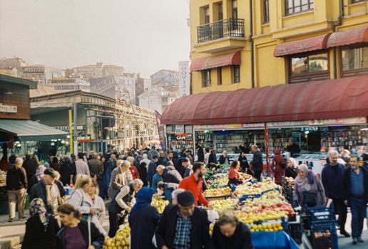 Lively outdoor market with bustling crowds and colorful produce stalls.