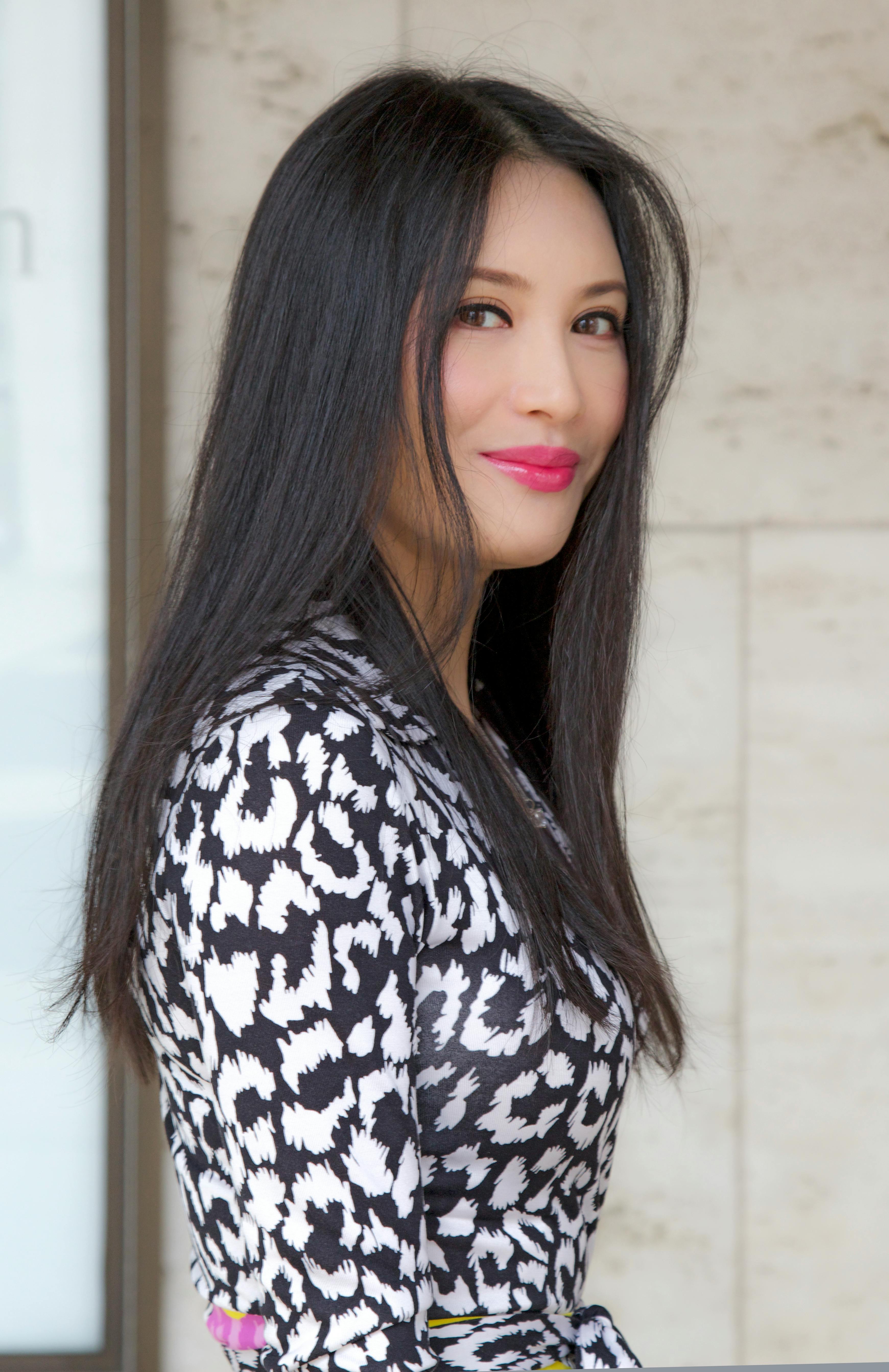 Stylish woman posing confidently indoors with a vibrant smile and chic fashion sense.
