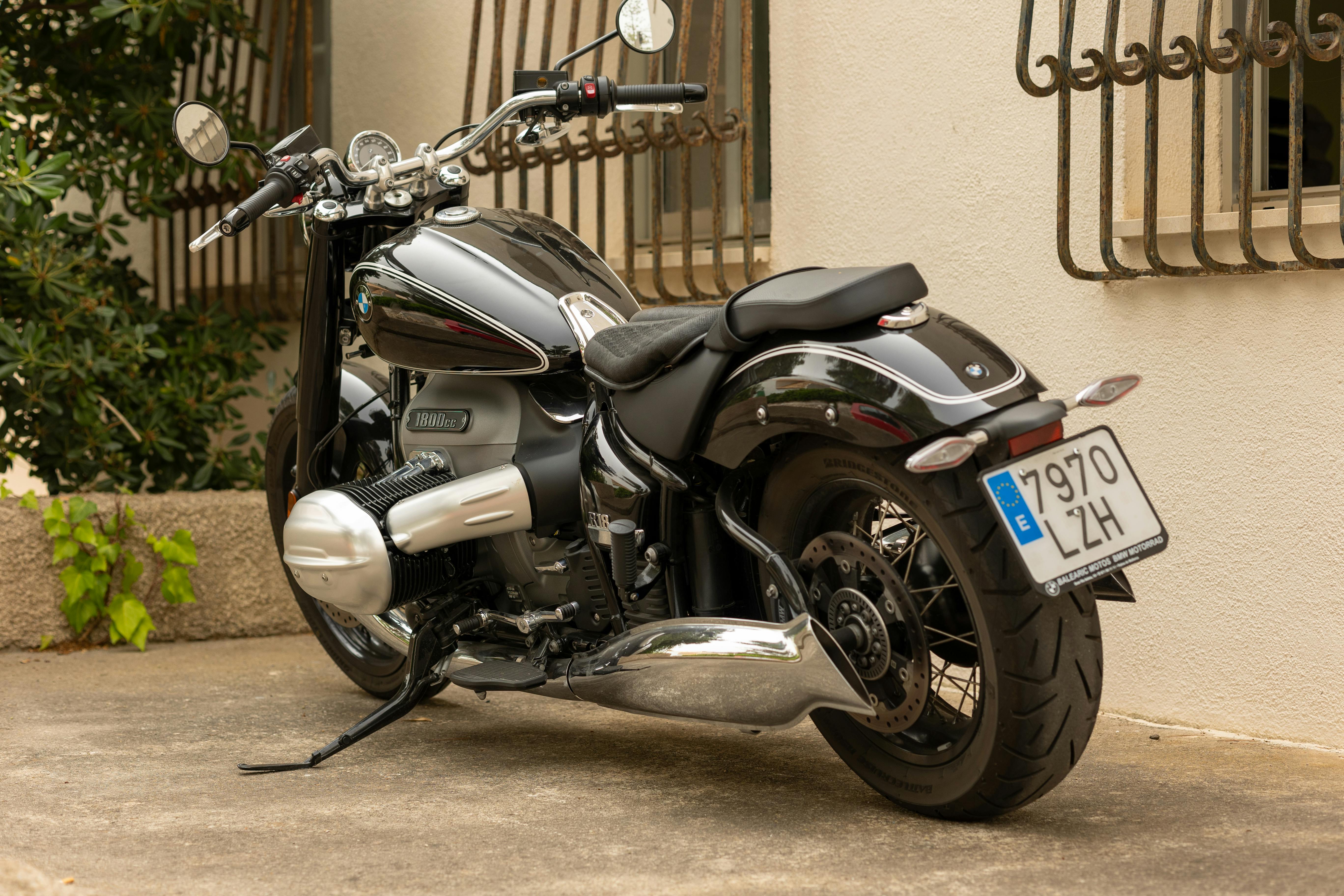 Free Side view of a parked motorcycle against a building wall in an urban setting. Stock Photo