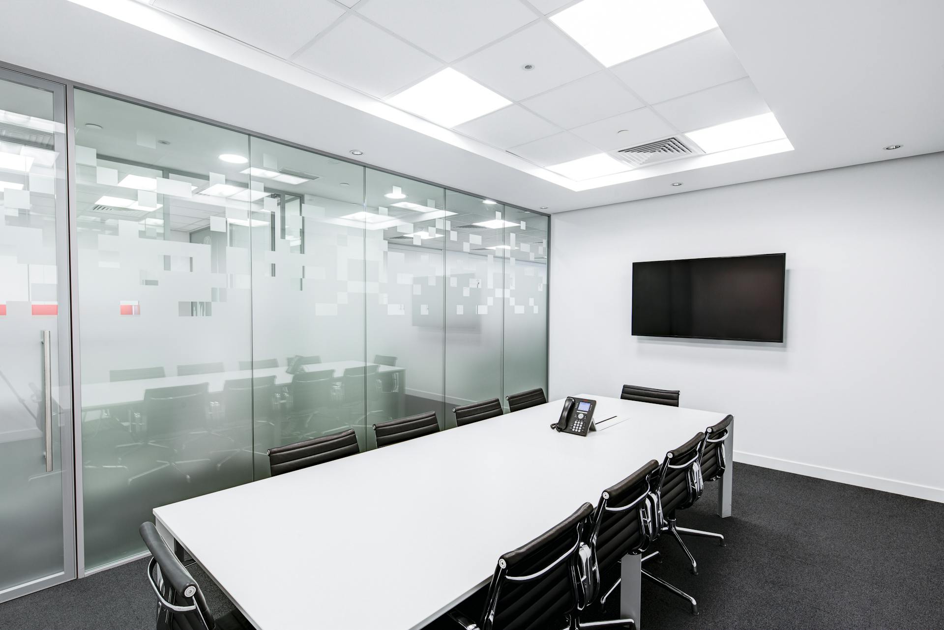 A sleek conference room with white table and rolling chairs