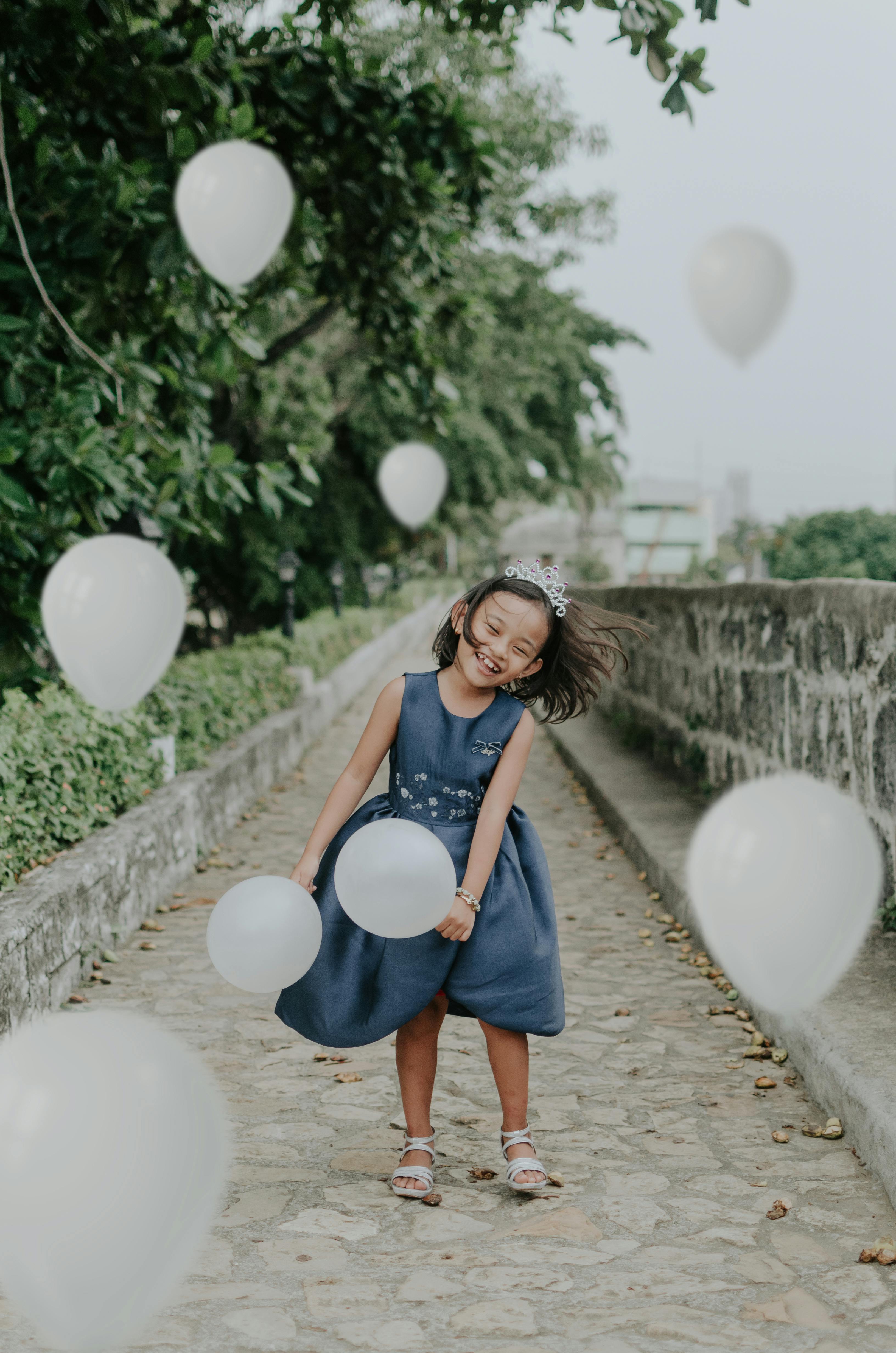 快乐的年轻女孩带着白色气球在户外庆祝生日