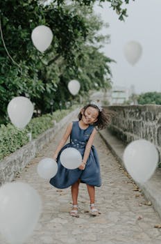 快乐的年轻女孩带着白色气球在户外庆祝生日