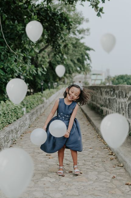 Cheerful young girl enjoying her birthday with white balloons in an outdoor setting.