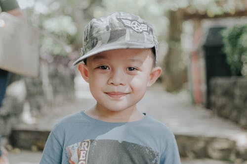 Selective Focus Portrait Photo of Smiling Boy in Camouflage Cap