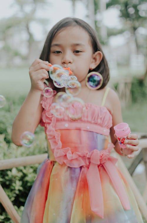 Девушка в разноцветном платье делает пузыри