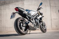 阳光明媚，一辆时尚的运动摩托车停在混凝土墙前