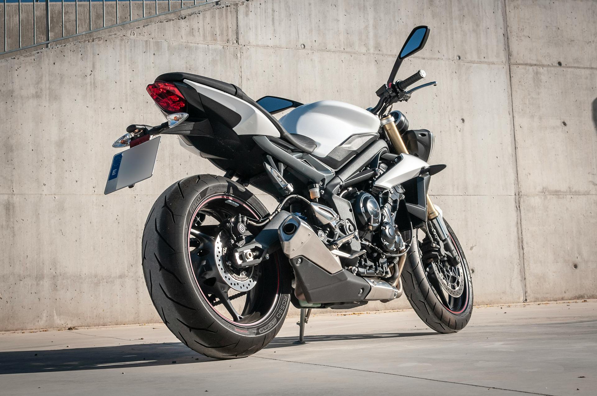 Photo of Black and Gray Naked Sports Bike Parked Besides Gray Concrete Wall