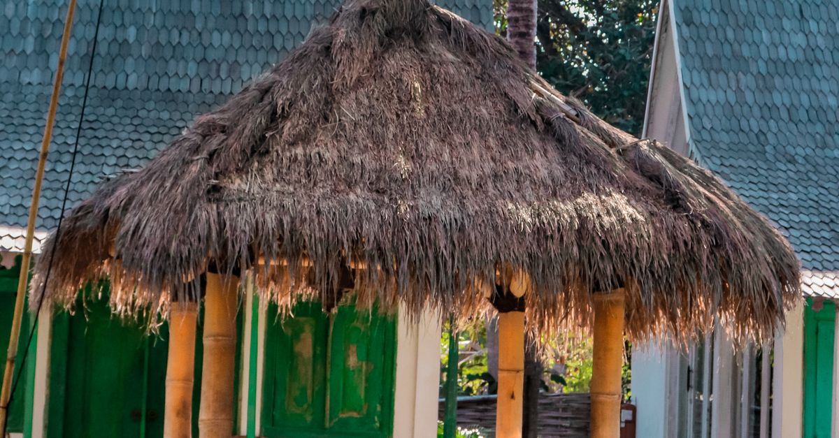 A woman relaxing in a tropical Bali resort hut by the pool surrounded by palm trees.